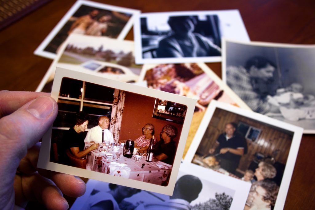 Mesa com fotos antigas de pai e filhos, representando a saudade e as memórias afetivas do Dia dos Pais